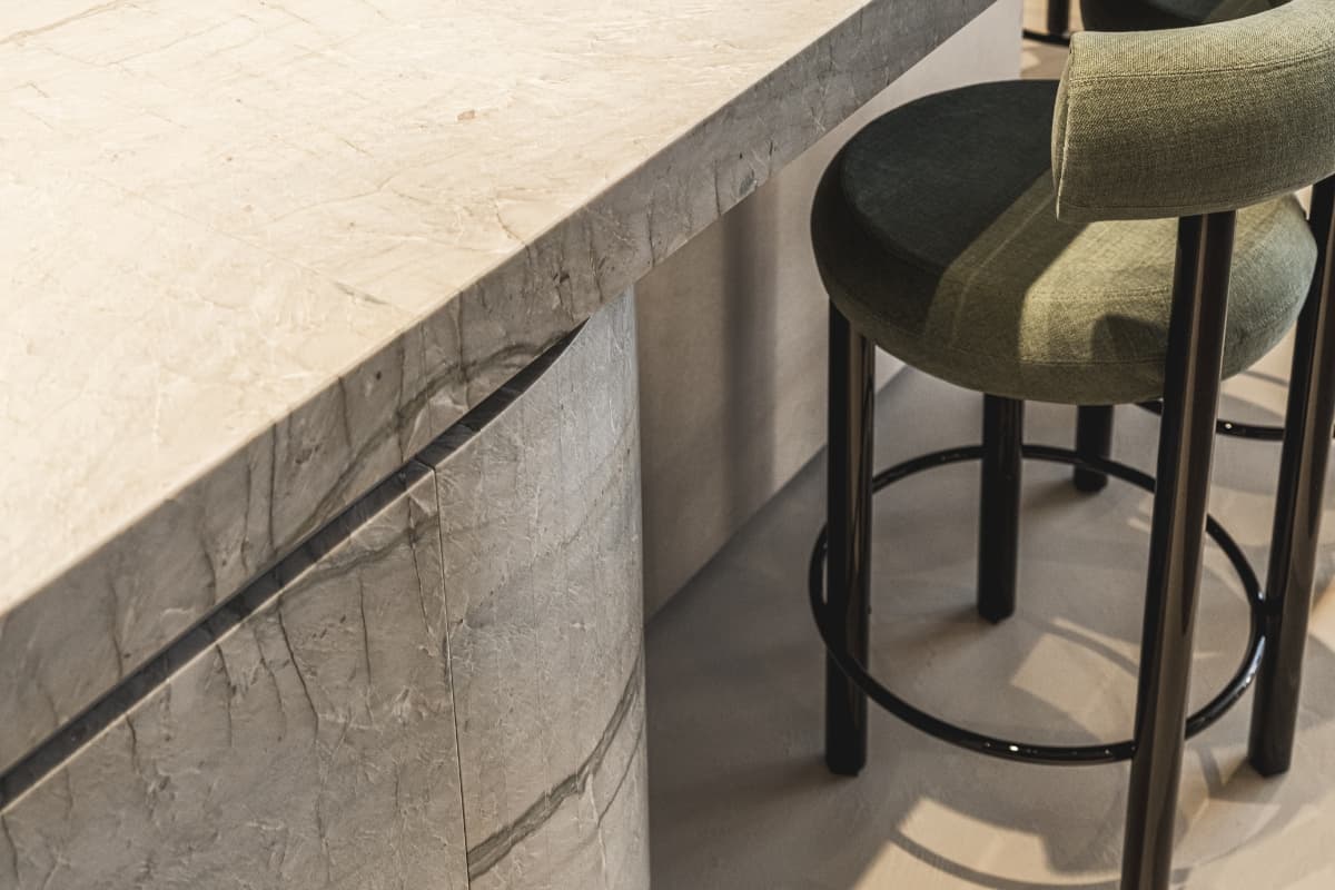 Ontwerp zonder titel (60).jpg Keukeneiland van beige marmer met een groen barkruk met zwarte poten